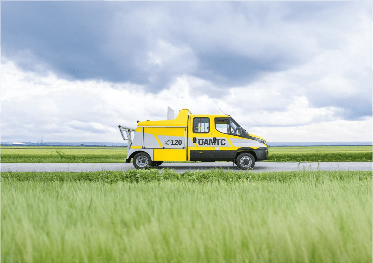 ÖAMTC roadside assistance vehicle driving through rural landscape, highlighting mobile breakdown service and in-vehicle technology