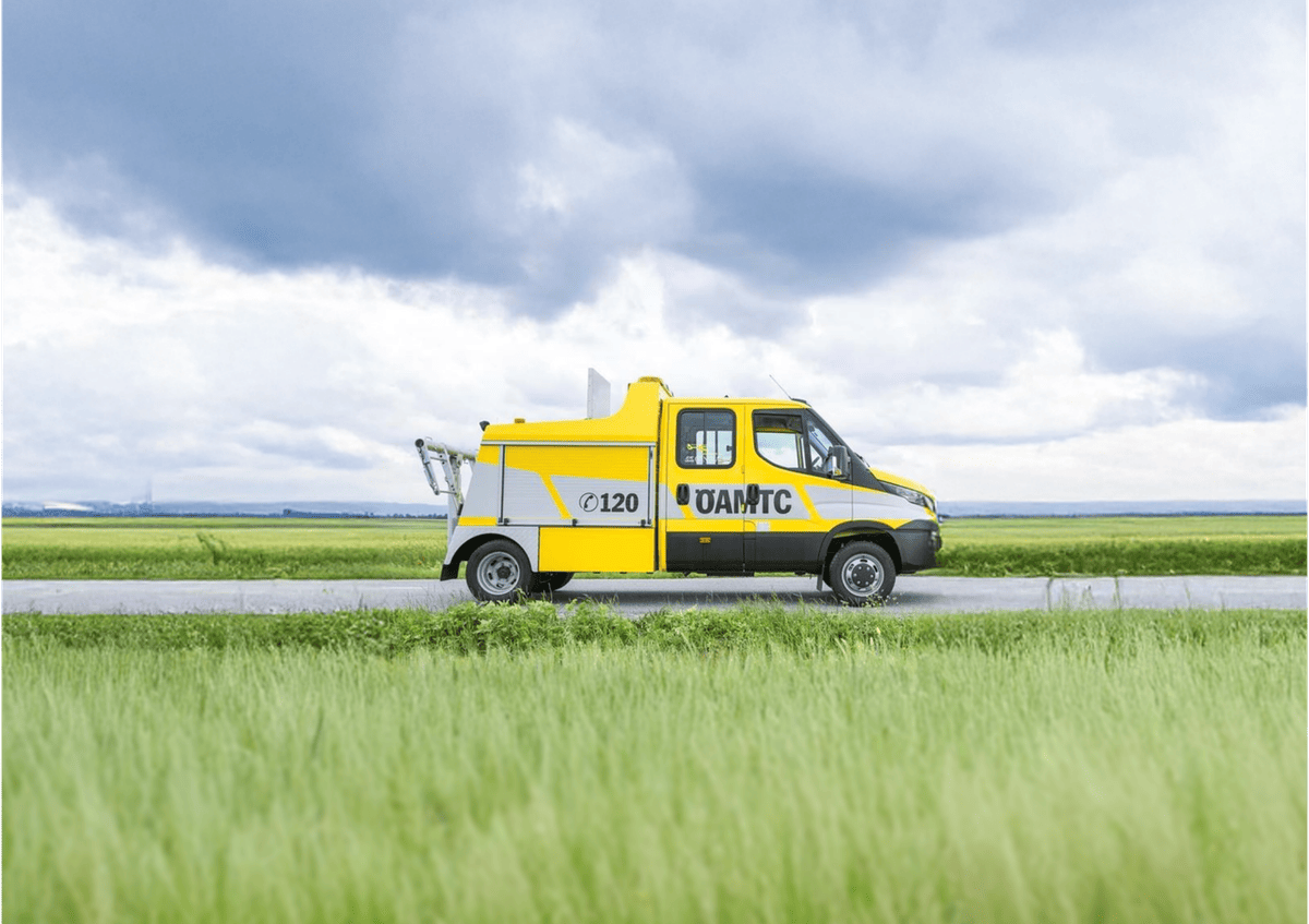 ÖAMTC roadside assistance vehicle driving through rural landscape, highlighting mobile breakdown service and in-vehicle technology